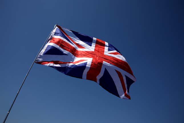 view from below a UK flag waving in the wind against a blue sky