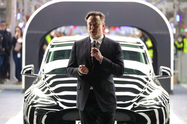 Tesla CEO Elon Musk stands in front of a car with zebralike lighting on it
