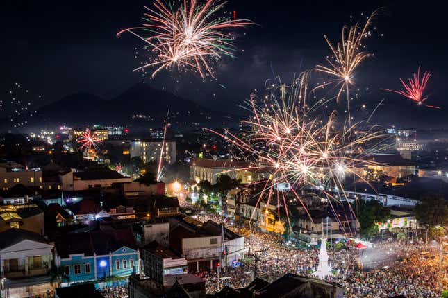 aerial view of fireworks against a night sky over a city with crowds of people in the street