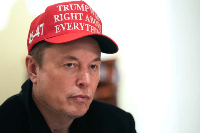 Close-up photo of Elon Musk wearing a red hat that says "Trump was right about everything"