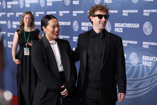 Mark Zuckerberg and Priscilla Chan both wear black suits as they walk down the red carpet