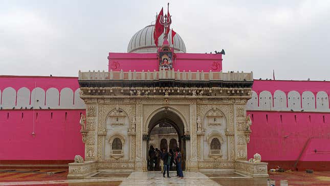 an ornate gate stands in front of hot pink walls