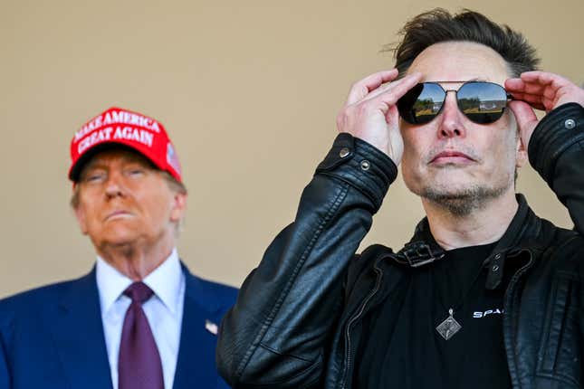 Elon Musk stands in front left of Donald Trump