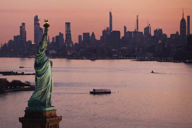 aerial view of the statue of liberty against the water and skyline of Manhattan